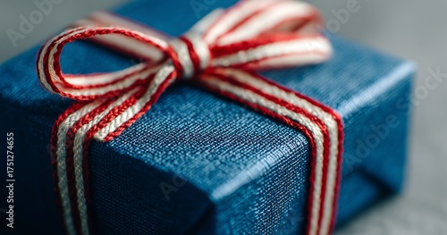 Gift Box With Red and White Ribbon on a Blue Surface in Soft Light