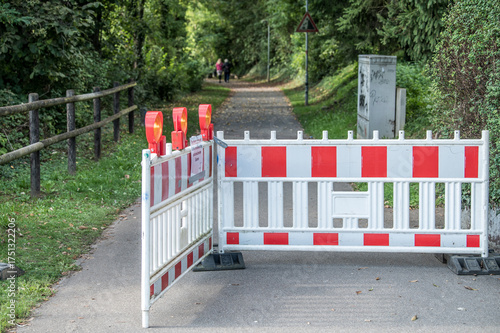 Geöffnete rot-weiße Absperrung Schrankenzaun mit Warnleuchten an Gehweg Hohlweg mit Warnschild Steinschlag und Holzzaun und grüner Vegetation am hohlen Stein in Neckartenzlingen.