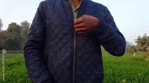 Boy zips up his jacket. The boy put on a blue jacket. Young boy is zipping up jacket. Caucasian handsome man wearing a Coat. Boy zipping up his jacket. green background.