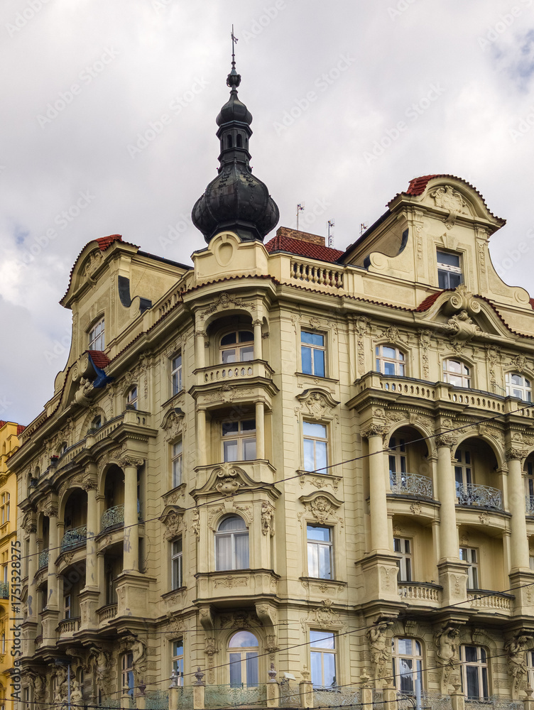 Obraz premium Detailed close-up of an elegant classical building facade featuring ornate stone carvings sculptures and a dark dome-shaped tower under a soft grey sky.
