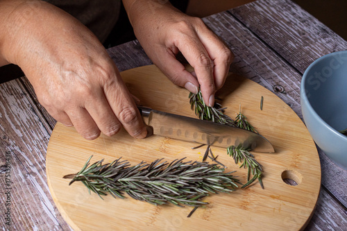 Manipulacion de alimentos, manejo de comida en la cocina, manos de mujer hispana mexicana trabajando con hierba romero, yerba natural vista lateral