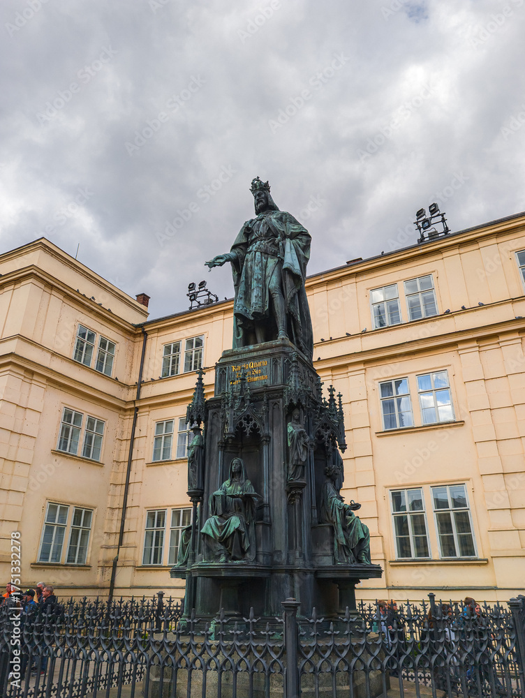 Fototapeta premium A monumental bronze statue of a historical monarch standing on an ornate stone pedestal decorated with allegorical figures in front of a classical building.