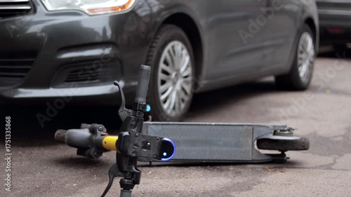 Yellow electric scooter lies on the ground after crash. Accident with car and electric scooter.