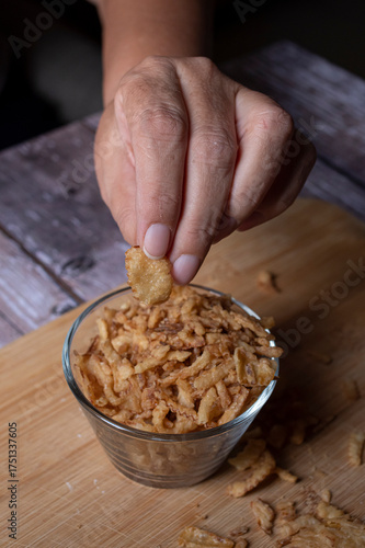 Manipulacion de alimentos, manejo de comida en la cocina, mano agarrando trozos de cebolla deshidratada, de un tazon de cristal sobre una tabla de cortar