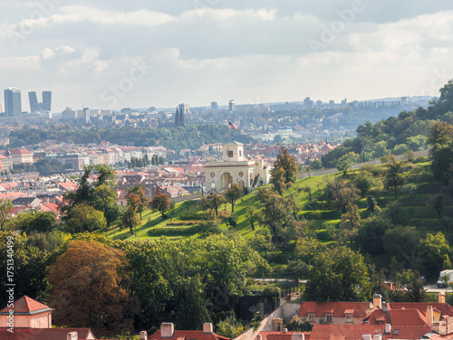 Bild auf Leinwand Panoramic view of an elegant white classical pavilion on a green hill overlooking a sprawling historical city with red roofs under a cloudy sky