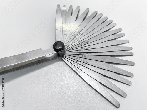 Close-up of a metal feeler gauge set on a light surface, used for precise measurement of small gaps in mechanical and engineering applications, measurement, quality and dimensional control
