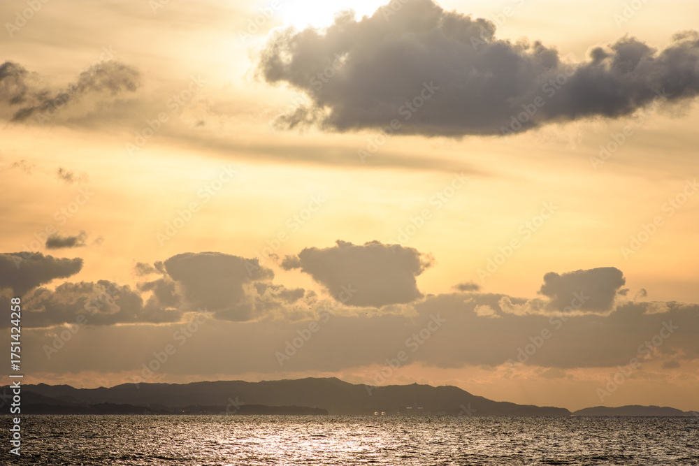 Fototapeta premium Serene Sunset Over Ocean with Silhouetted Hills
