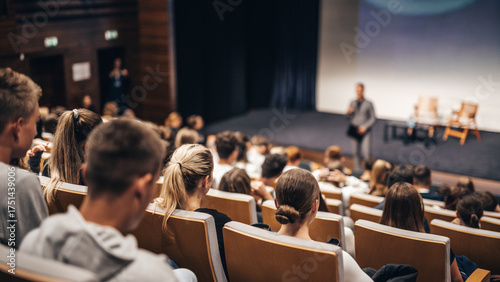 Speaker giving a talk in conference hall at business event. Rear view of unrecognizable people in audience at the conference hall. Business and entrepreneurship concept