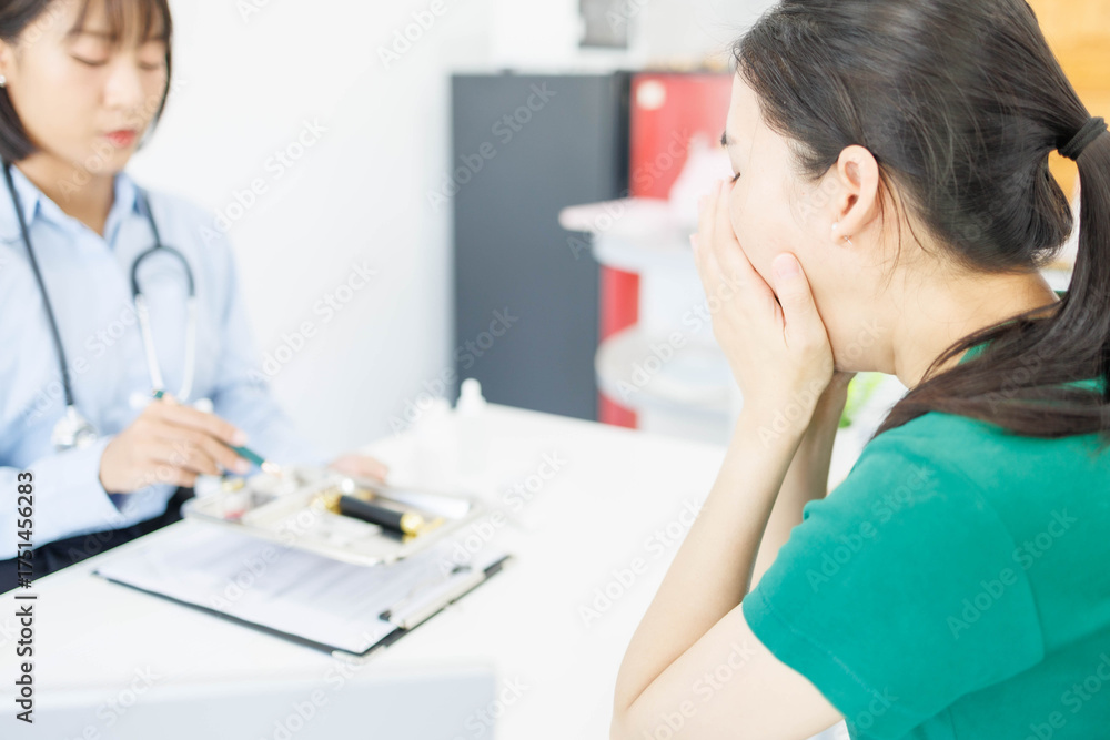 Obraz premium A woman is handing a tray of medical supplies to another woman. The tray contains a pen, a bottle, and a pair of scissors. The scene suggests a medical setting 