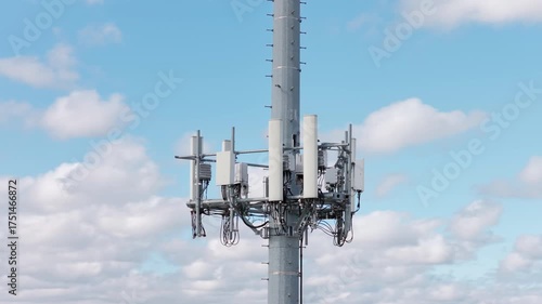 Aerial orbit view of mobile phone cell tower against blue sky with white clouds, low angle view