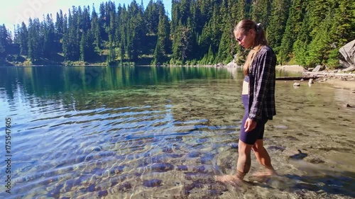 A young girl enjoys the clear, refreshing waters of Lake Valhalla, walking barefoot along its edge as part of her adventure on the Pacific Crest Trail in Washington