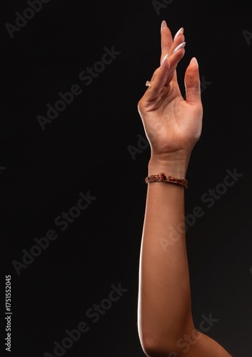 Woman's arm extended with delicate hand gesture on black background