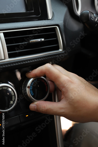 close up hand air conditioning and center console of car for temperature.