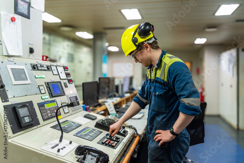 Young marine engineer during his daily routine work in engine room. Seafarers life.