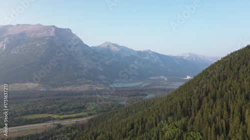 Cinematic drone footage captures the raw beauty of a remote mountain wilderness. The camera glides over treetops to showcase the vast, layered landscape of the valley and peaks.