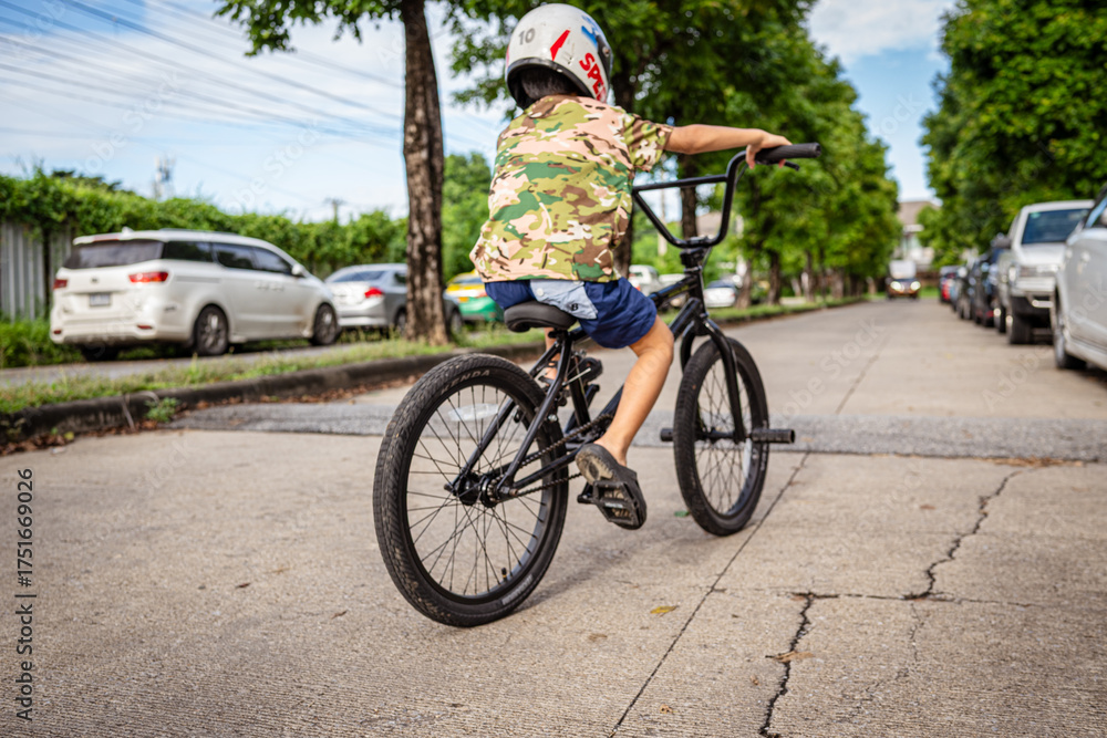 Fototapeta premium Asian school boy practice ride bicycle in city village garden