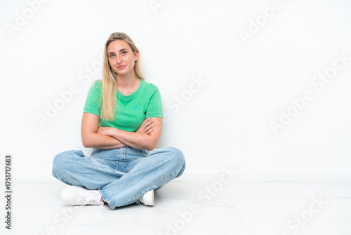 Canvas Print Young caucasian woman sitting on the floor isolated on white background keeping