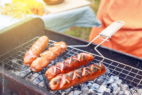 Valokuva Grilled sausages are sizzling on a barbecue grill filled with glowing coals