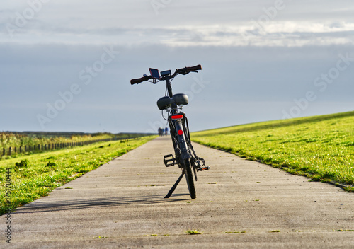 E-bike resting on a concrete path along a grassy dike near the north sea in carolinensiel, germany
