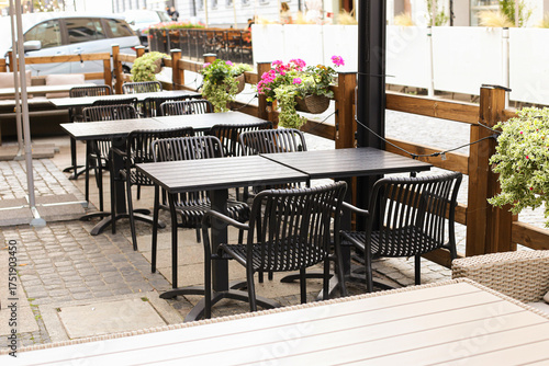Empty outdoor cafe terrace with tables and chairs. Relaxing urban place for coffee and social meeting. Cozy restaurant patio scene in sunlight. Modern dining area concept.