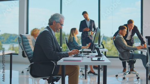 Wallpaper Mural Diverse business people actively working and collaborating on computers in a bright, modern office space, fostering teamwork and professional productivity during daytime Torontodigital.ca