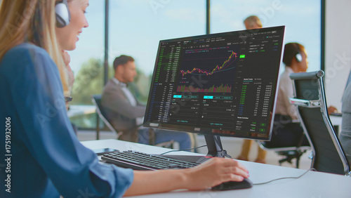 Wallpaper Mural Businesswoman wearing headphones monitoring stock market data and analyzing financial charts on a computer screen, trading investments in a contemporary office Torontodigital.ca