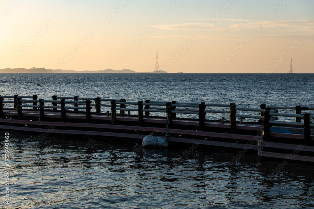 Fototapeta premium idyllic seascape with island, pylon and pier during sunset