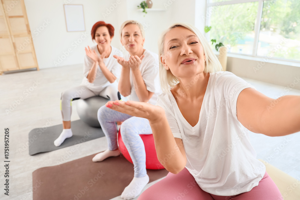 Obraz premium Mature women taking selfie on fitballs at gym