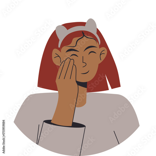 young woman with red hair and a headband smiles while applies face cream. concept self-care. She wears a light-colored top, conveying a playful and cheerful mood