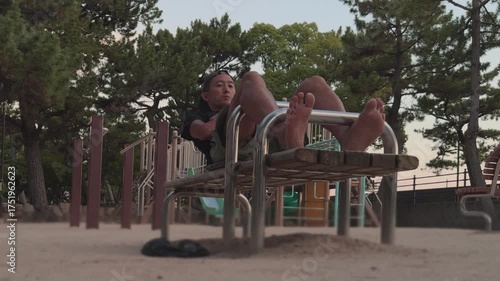 A man performing sit-up exercises on a workout bench in a public park