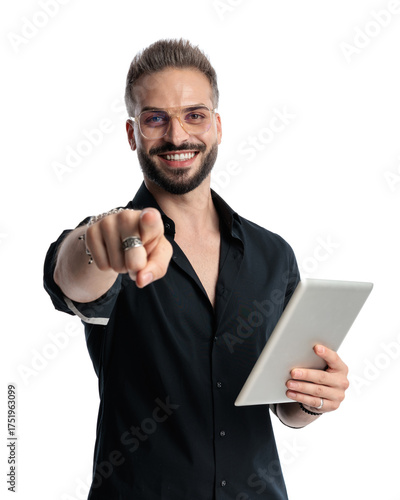 happy casual man with glasses holding tablet and pointing finger forward