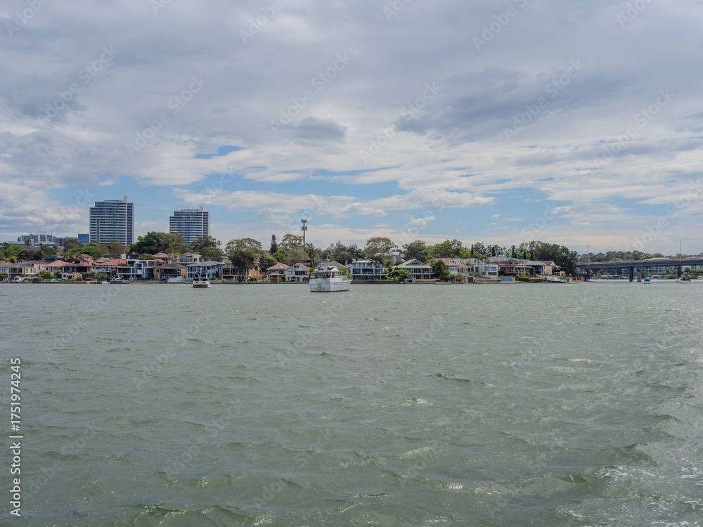 Obraz premium 11 October 2025 Residential Houses and apartment and commercial buildings on Parramatta River Sydney Harbour on a warm spring cloudy overcast day in Sydney NSW Australia