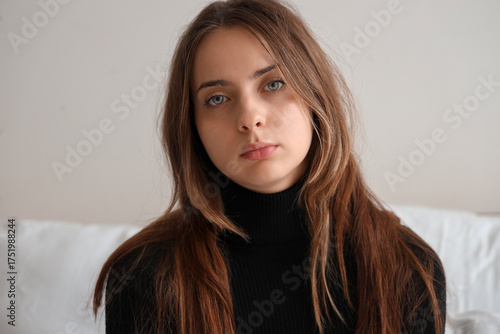 Sad young woman in bedroom,...