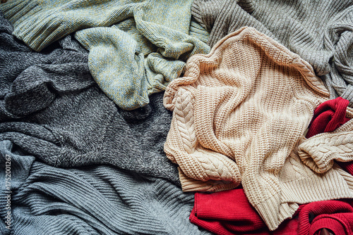 Overhead view of mixed knitwear heap demonstrating clothing donation sorting or storage preparation. Charity contribution activity and secondhand fashion circulation. Sustainable wardrobe practice.
