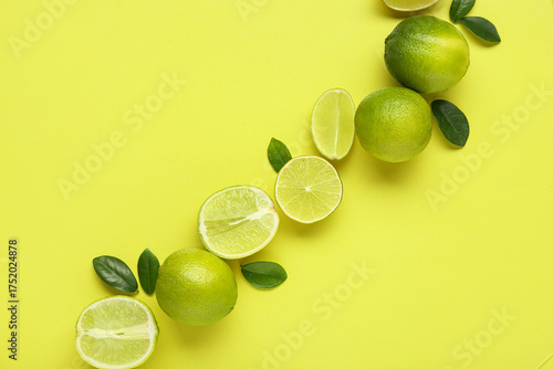 Tablou pe pânză Fresh ripe limes and leaves on green background