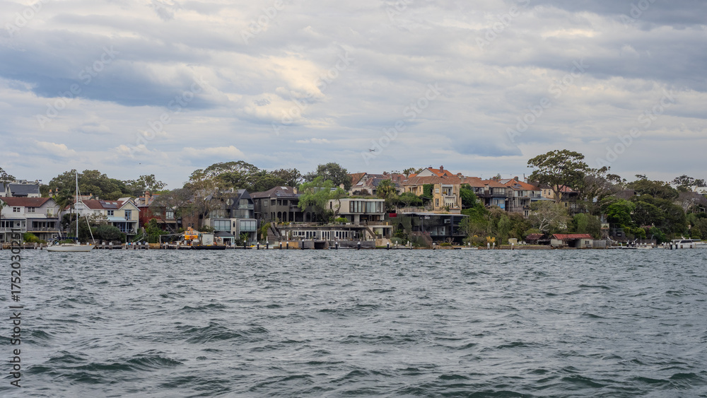 Fototapeta premium Residential Houses and apartment buildings on Parramatta River Sydney Harbour on a warm spring cloudy overcast day in Sydney NSW Australia