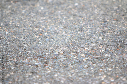 Granular Pavement Texture: A detailed, close-up view of rough granular asphalt pavement, revealing a rich texture perfect for conveying concepts of urban landscapes or industrial settings. 