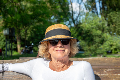 Wallpaper Mural very attractive sixty year old lady with hat sitting at a bench and enjoying the sun Torontodigital.ca