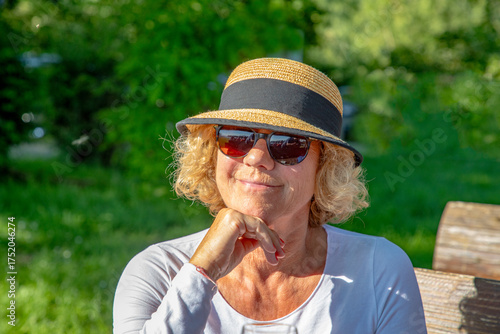 Wallpaper Mural very attractive sixty year old lady with hat sitting at a bench and enjoying the sun Torontodigital.ca