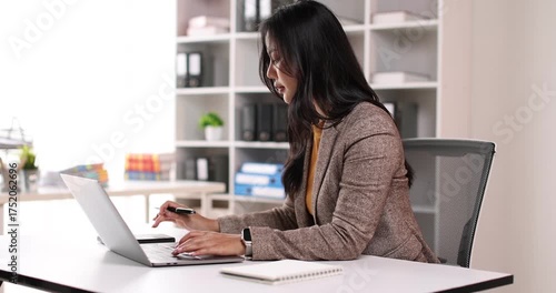Adult woman working at her desk in a bright office, business casual jacket digital nomad remote work concept
