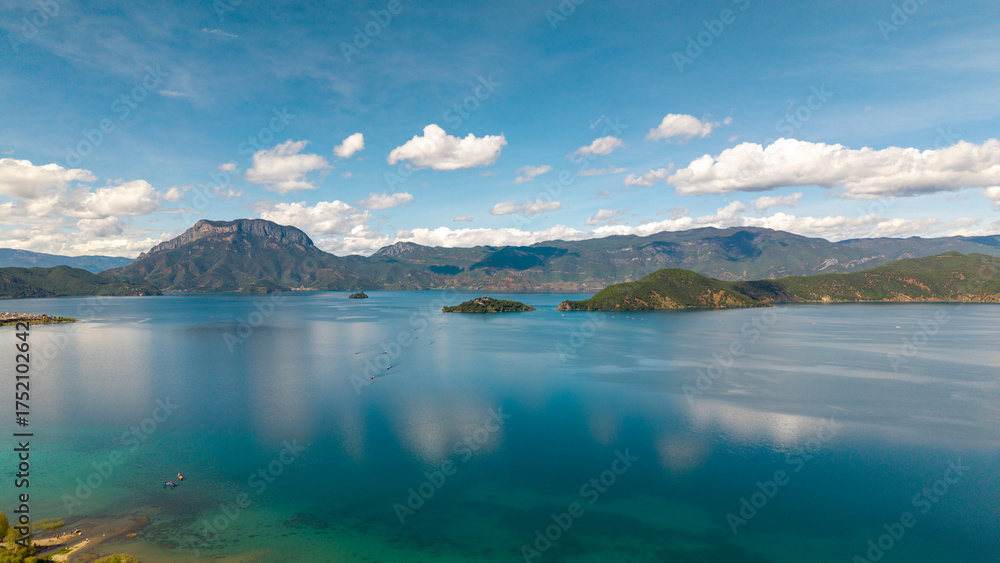 Obraz premium Villages by the Sunrise Lake and distant mountains, Lugu Lake in Sichuan, China