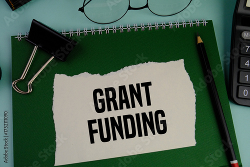 Business financing and grants concept. Copy space. GRANT FUNDING on a white torn paper on the green background 