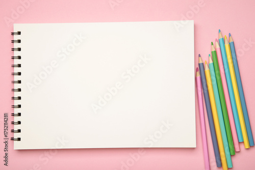 Sketchbook and colored pencils on pink background