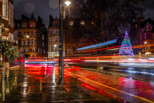 Photography Classic red double-decker bus on festive London street at night