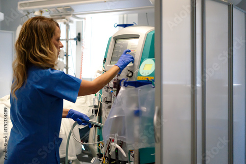 Nurse adjusting dialysis machine in hospital room