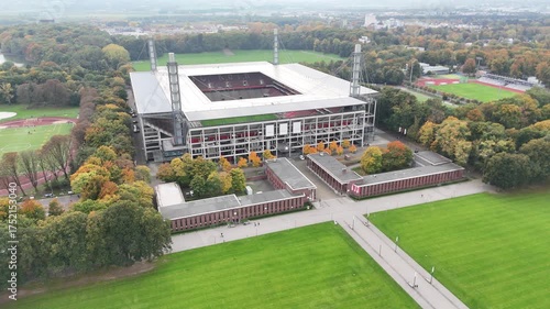 Cologne, Germany - 12 October, 2025: aerial view of a modern Muengersdorf football stadium aligned with a central walkway and lawns, set within a forested urban park. No people. Symmetry