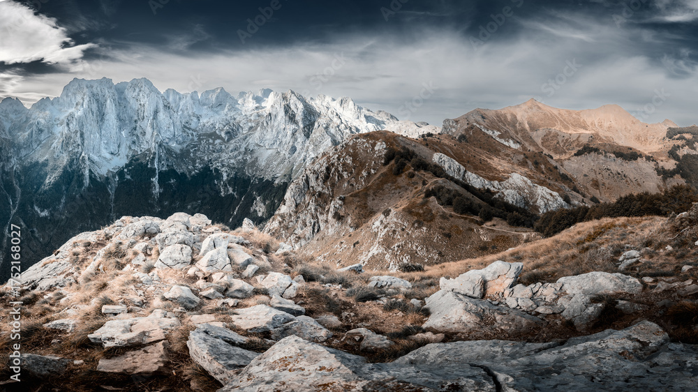 Obraz premium Sunlit hilltop with view to rocky mountain ridge on sunny day, Prokletije, Montenegro