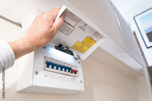 Close-up of a modern, domestic fuse and circuit breaker cabinet in a typical household. Various electrical devices are controlled protected by the blue breakers. The red switch for power isolation.
