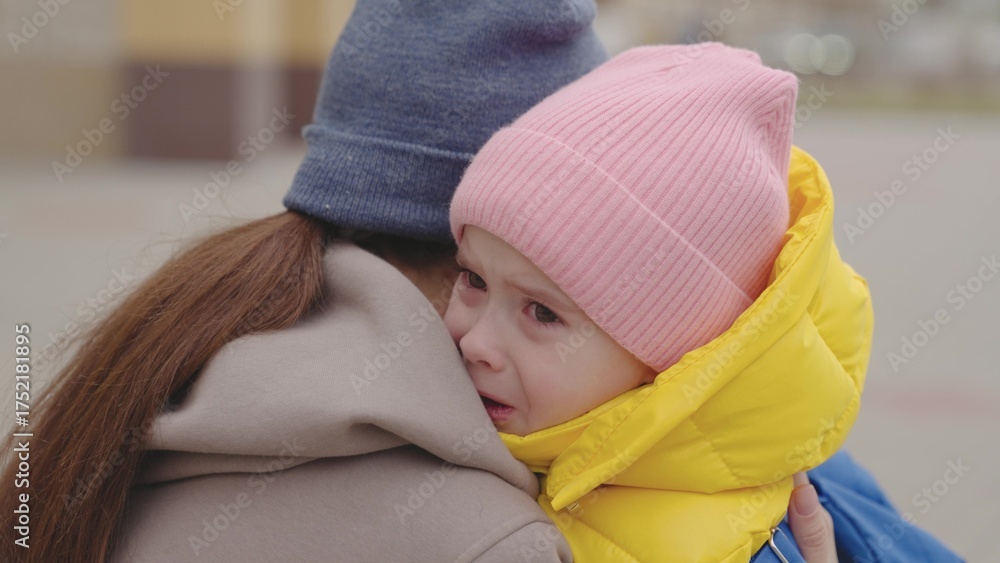 Φωτογραφία mother soothes a crying little child, mom wipes tears running down her face and hugs a kid with a backpack, educational school program, worry about lessons and grades, baby in the arms of a parent