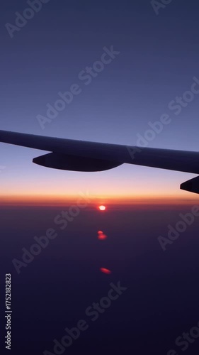 4K, View of plane wing with the sunset through an airplane window in flight trip, traveling by air. Plane flying with beautiful dawn sun. Vacation journey concept